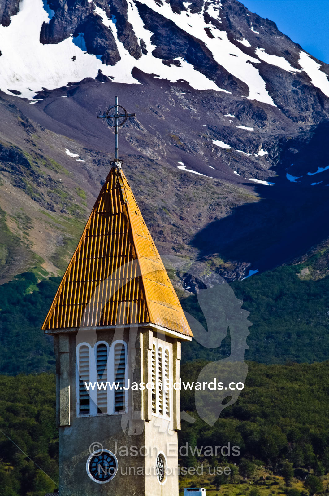A bright yellow church steeple beneath the snowy peaks of the Andes. Nuestra Se��ora de la Merced, Ushuaia, Martial Mountains, Fuegian Andes, Ushuaia Bay, The Beagle Channel, Tierra del Fuego Archipelago, Straits of Magellan, Tierra del Fuego Province, Patagonia, Argentina.