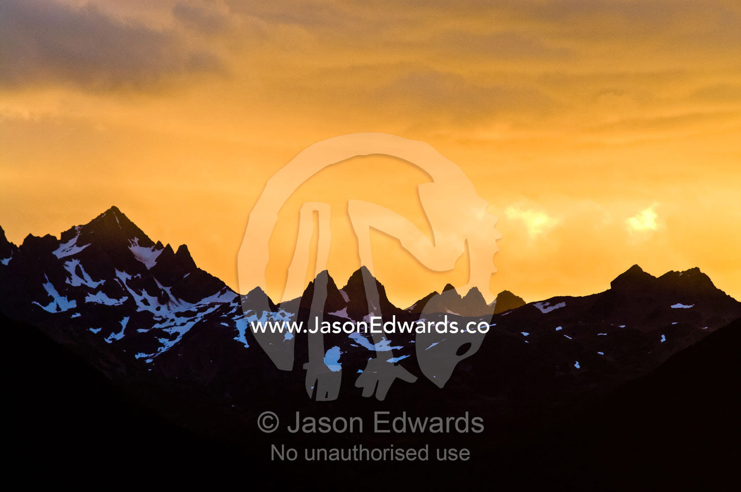 Sunset descends over a horizon of jagged Andean mountain peaks. Chilean Andes, Fuegian Andes, The Beagle Channel, Tierra del Fuego Archipelago, Straits of Magellan, Tierra del Fuego Province, Patagonia, Argentina.