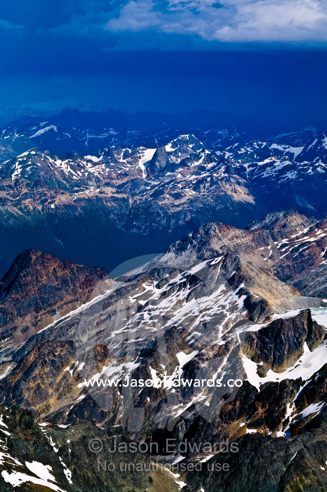 Dappled patches of cloud and sunlight on jagged snowy mountain peaks. Ushuaia, Martial Mountains, Fuegian Andes, Tierra del Fuego Archipelago, Straits of Magellan, Tierra del Fuego Province, Patagonia, Argentina.