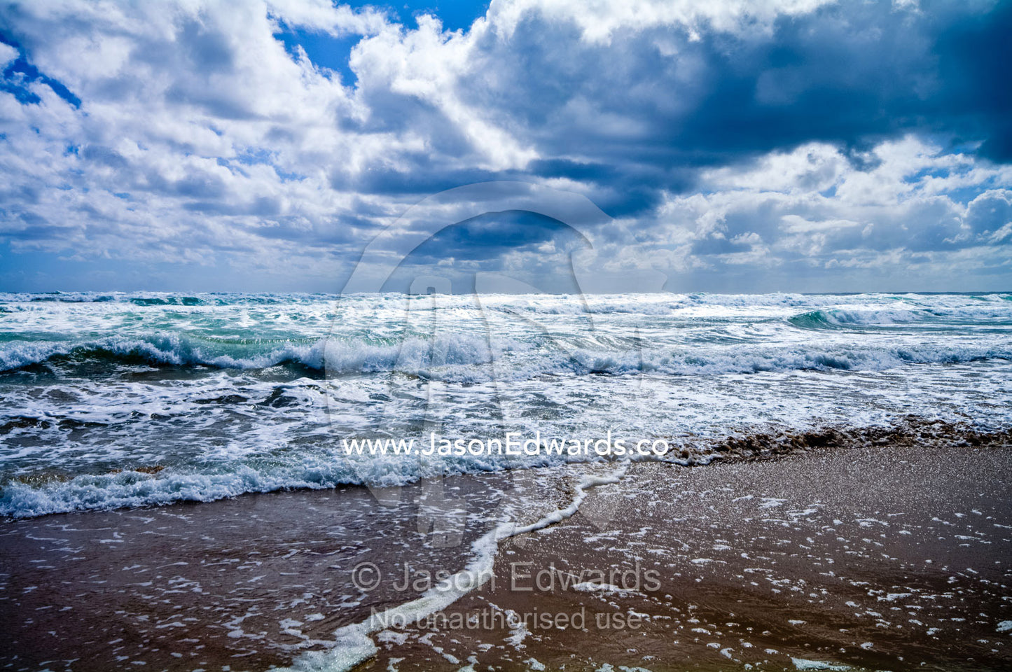 Foam and waves splash onto a sandy beach during a summer storm. Venus Bay, Cape Liptrap Coastal Park, Bass Strait, South Gippsland, Victoria, Australia.