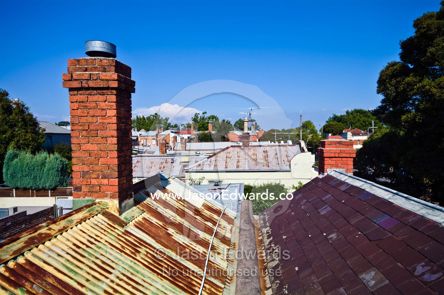 A Victorian red brick chimney pitched on a rusty corrugated iron roof. Carlton North, Melbourne, Victoria, Australia.