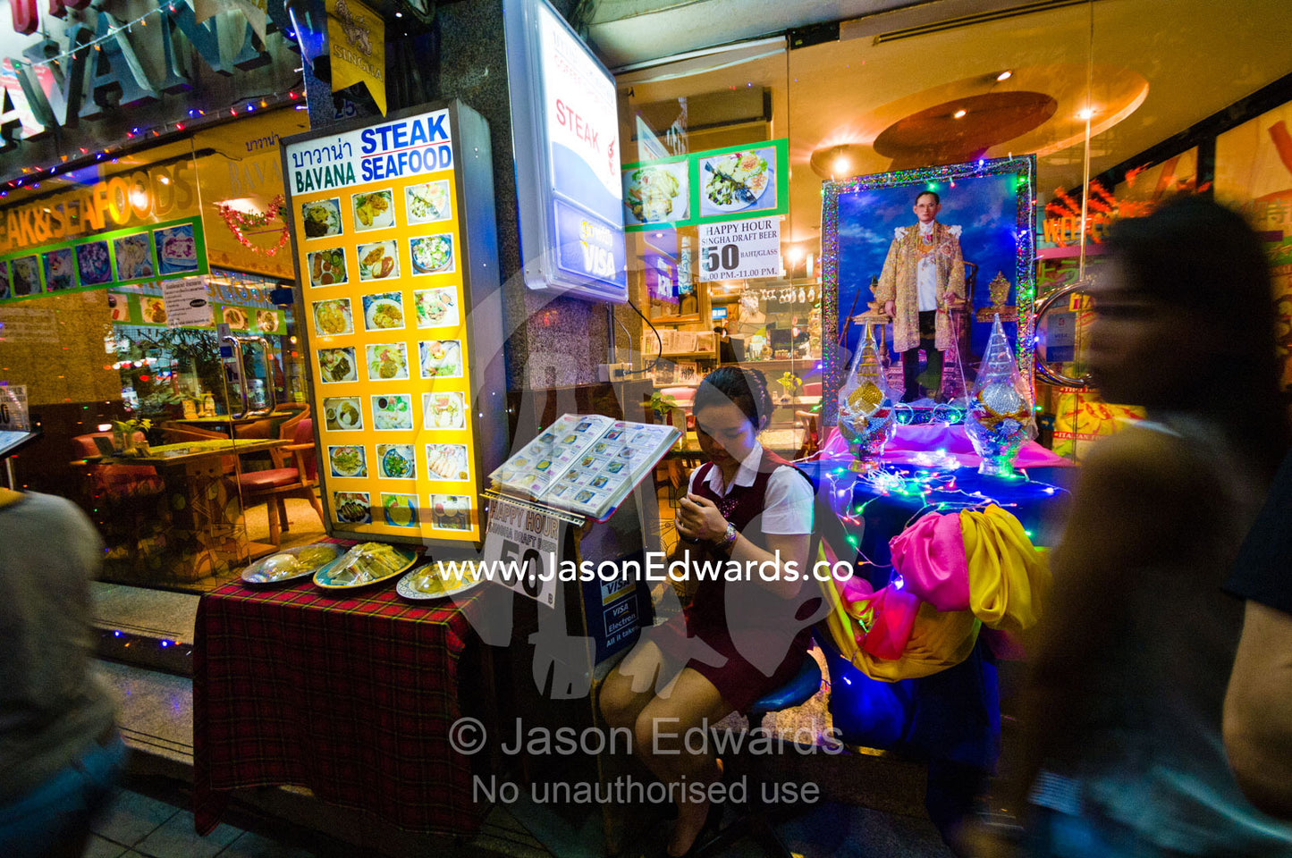 A busy street restaurant hostess texts a message on her mobile phone. MBK Centre, Mahboonkrong Shopping Center, Bangkok, Thailand.