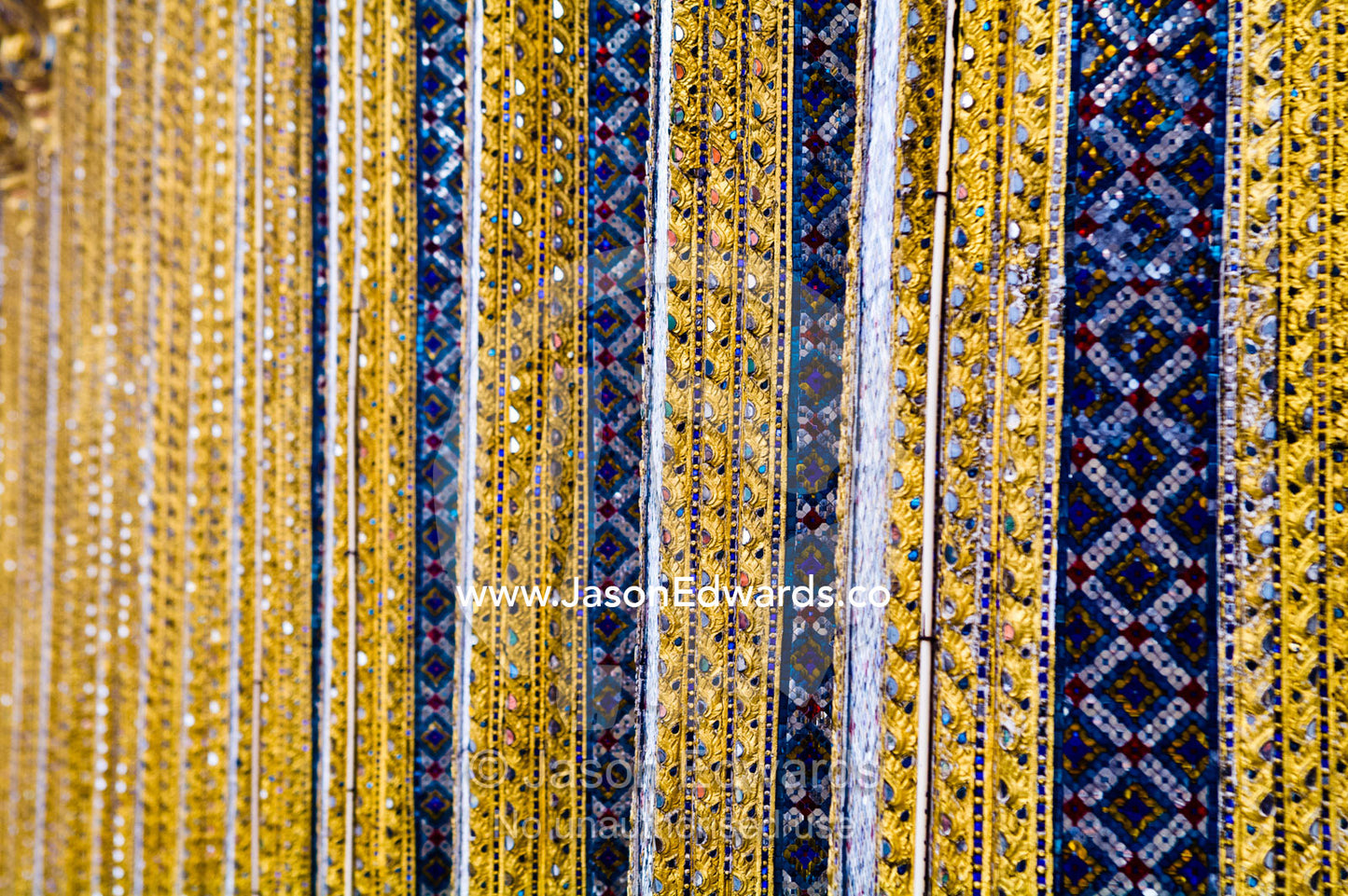 Glass tile mosaic and gold leaf decorate ornate pillars of a temple. Prasat Phra Thep Bidon, Royal Pantheon, Wat Phra Kaew, Wat Phra Kaeo, Temple of the Emerald Buddha, Bangkok, Thailand.