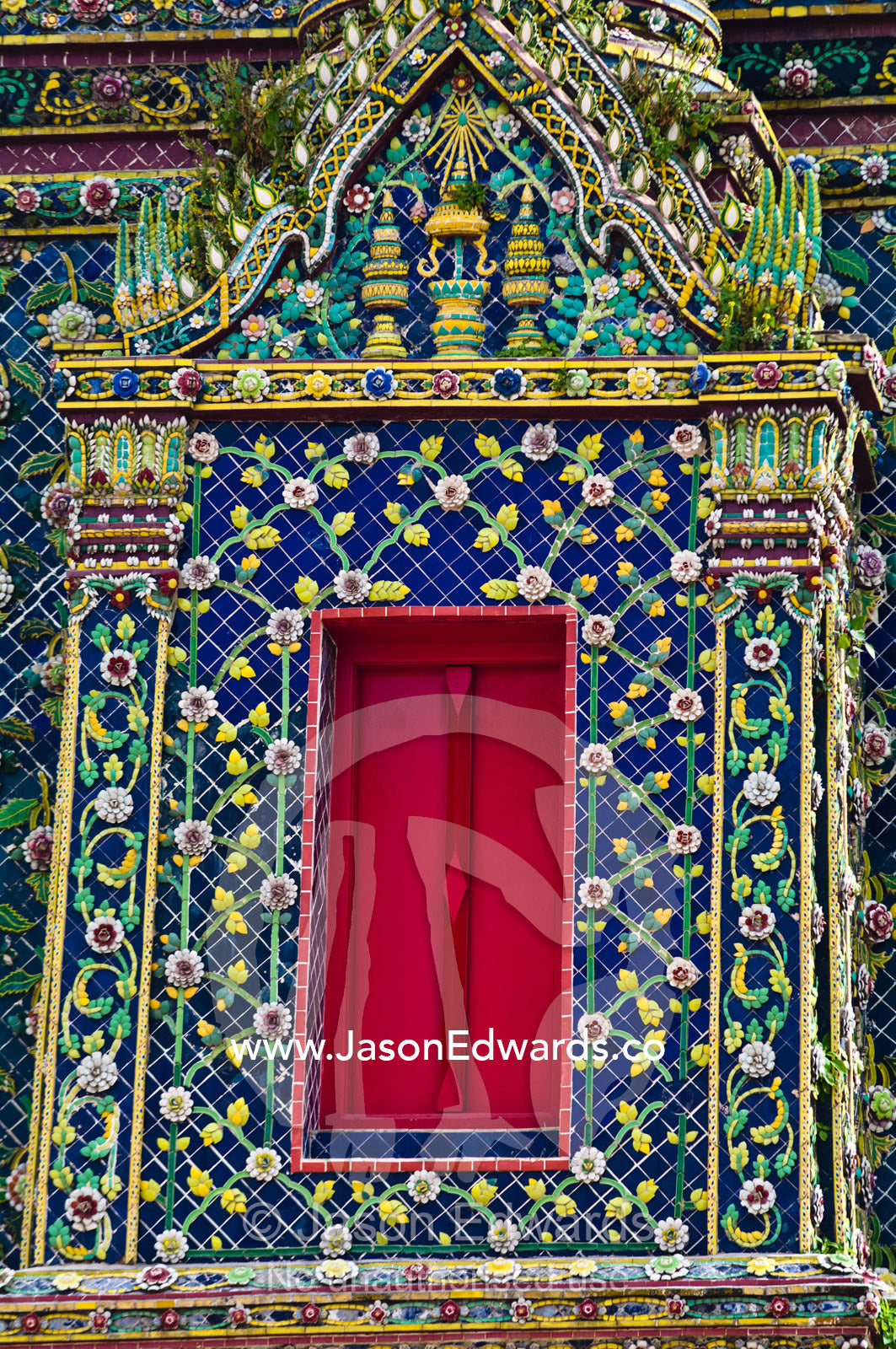 A bright red door high on the wall of an ornately decorated prang. Wat Pho, Temple of the Reclining Buddha, Wat Chetuphon, Phra Nakhon District, Rattanakosin District, Bangkok, Thailand.