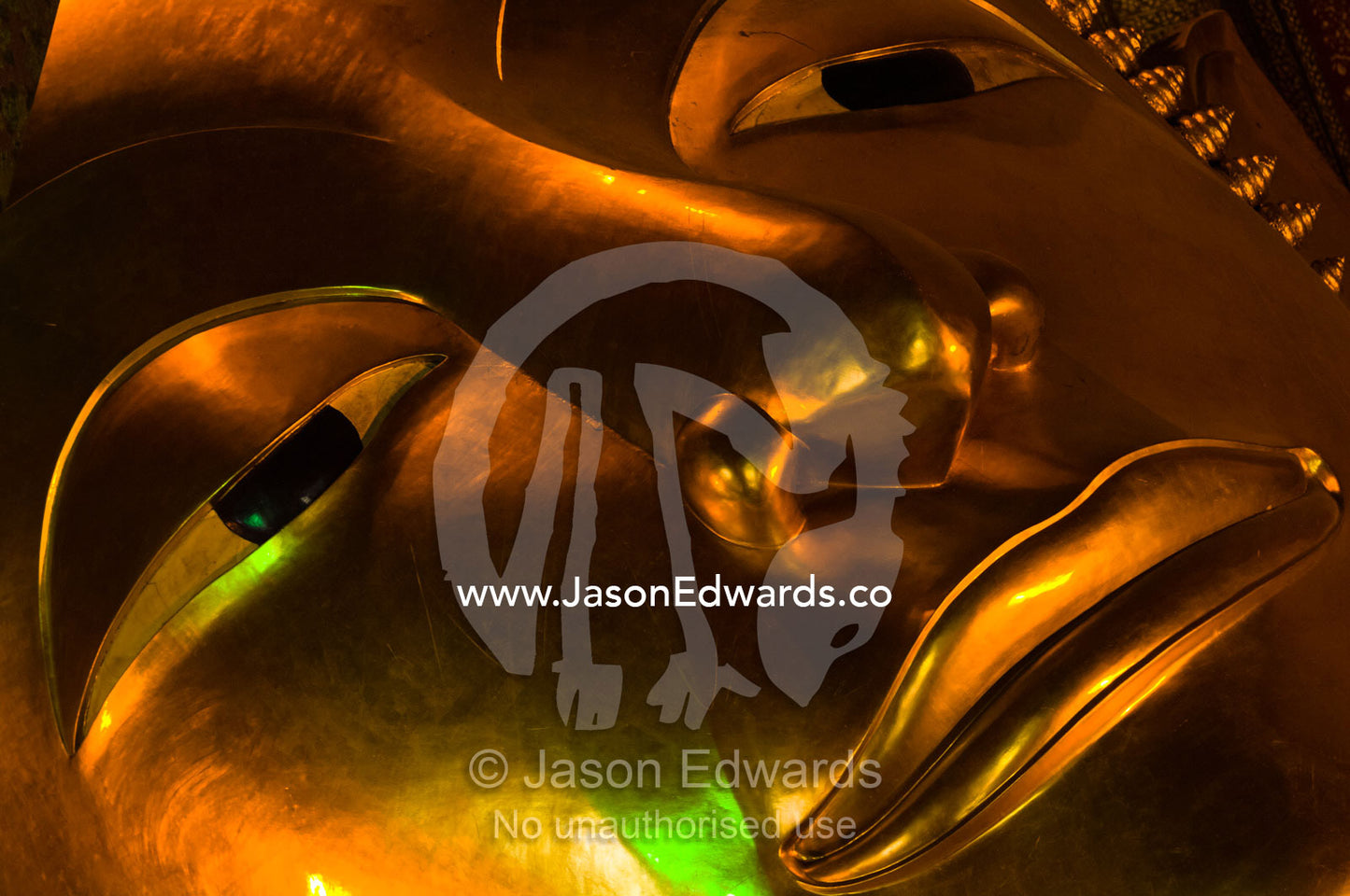 A close-up of the eye, nose and mouth of the Reclining Buddha statue. Wat Pho, Temple of the Reclining Buddha, Wat Chetuphon, Phra Nakhon District, Rattanakosin District, Bangkok, Thailand.