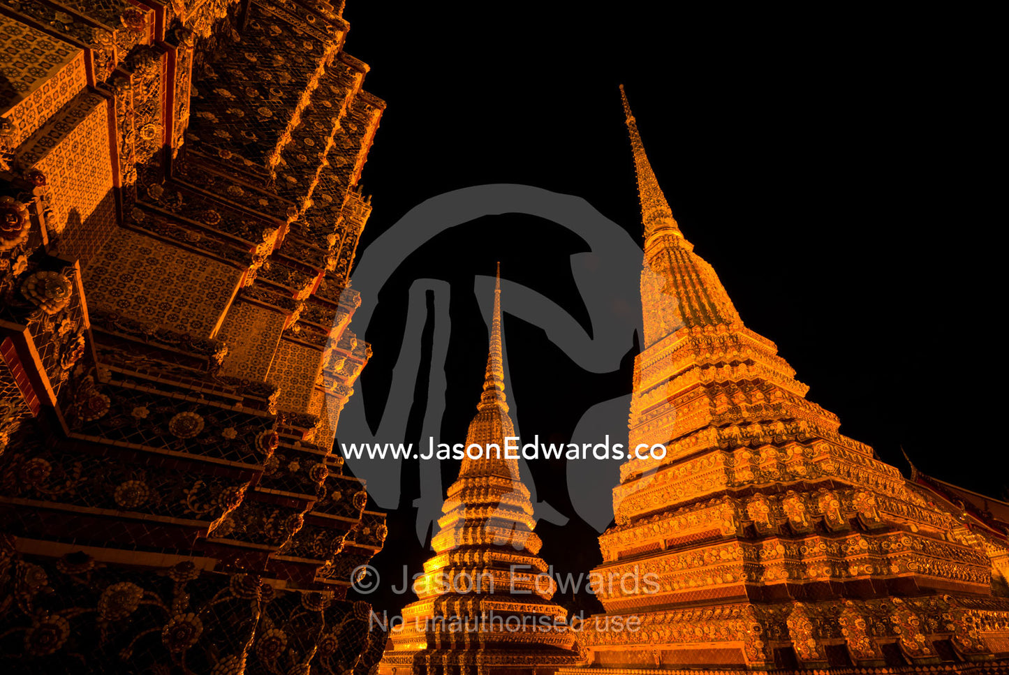 Floodlights on the prang of the Phra Maha Chedi rising into night sky. Wat Pho, Phra Maha Chedi, Bangkok, Thailand.