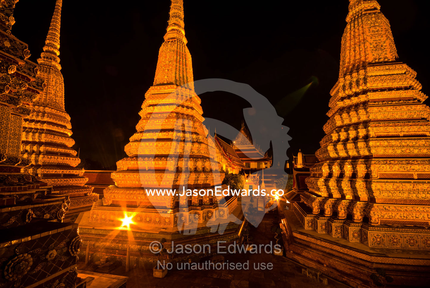 Floodlights on the prang of the Phra Maha Chedi rising into night sky. Wat Pho, Phra Maha Chedi, Bangkok, Thailand.