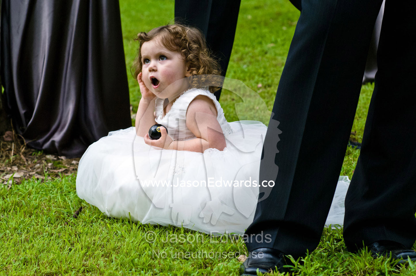 A flower girl rests whilst eating chocolate at a garden wedding. Park Orchards, Melbourne, Victoria, Australia.