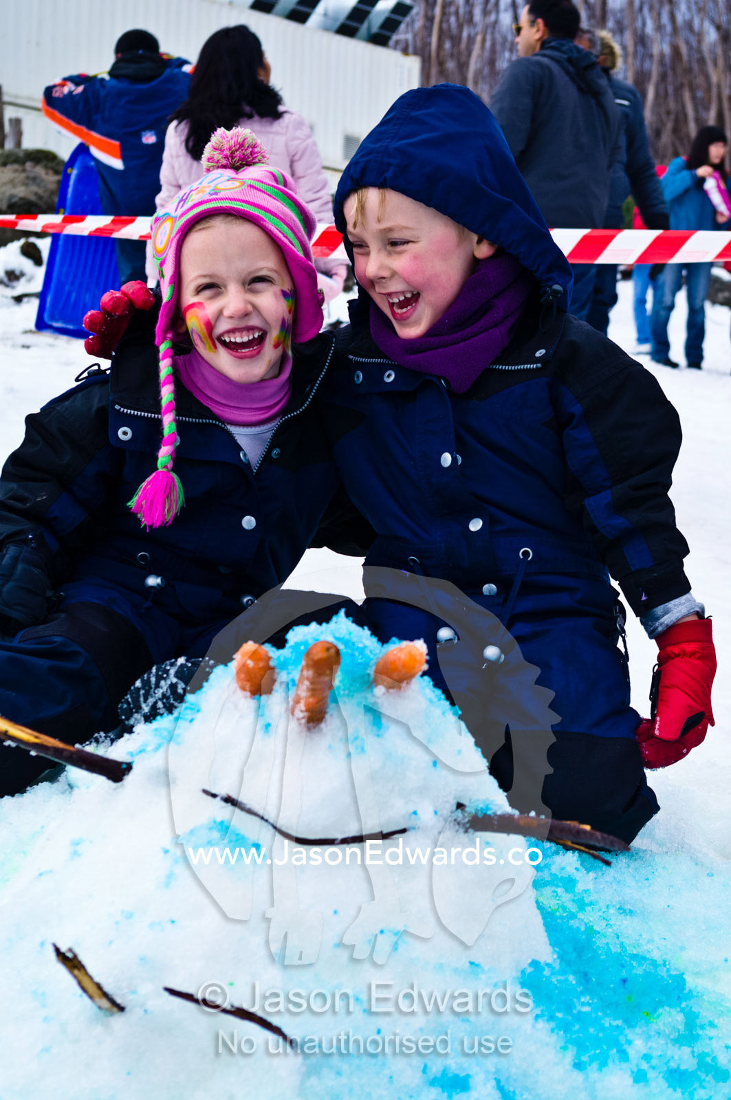 Young friends laughing at their snow man died blue with food dye. Lake Mountain, Yarra Ranges National Park, Victoria, Australia.