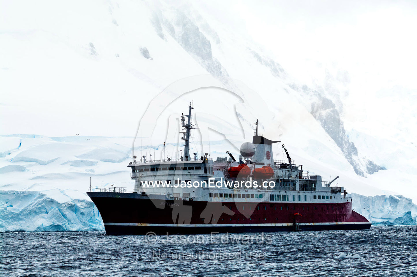 An Antarctic cruise ship anchored by a snow and ice encrusted peak. Crystal Sound, Hanusse Bay, Antarctic Peninsula, Antarctic Circle, Antarctica.