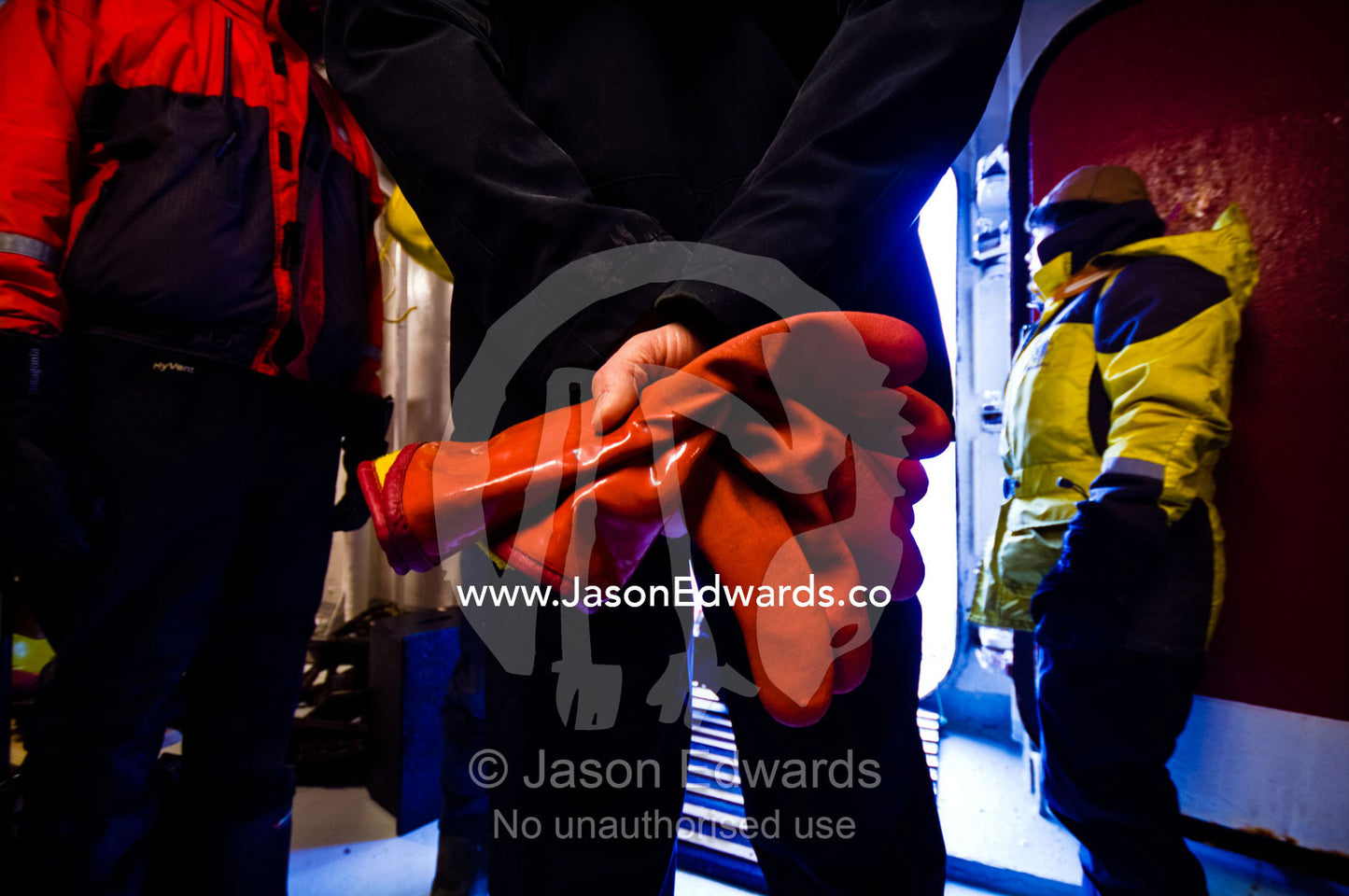 An Antarctic expedition leader with rubber gloves waits by a hull door. Prospect Point, Crystal Sound, Antarctic Peninsula, Antarctic Circle, Antarctica.