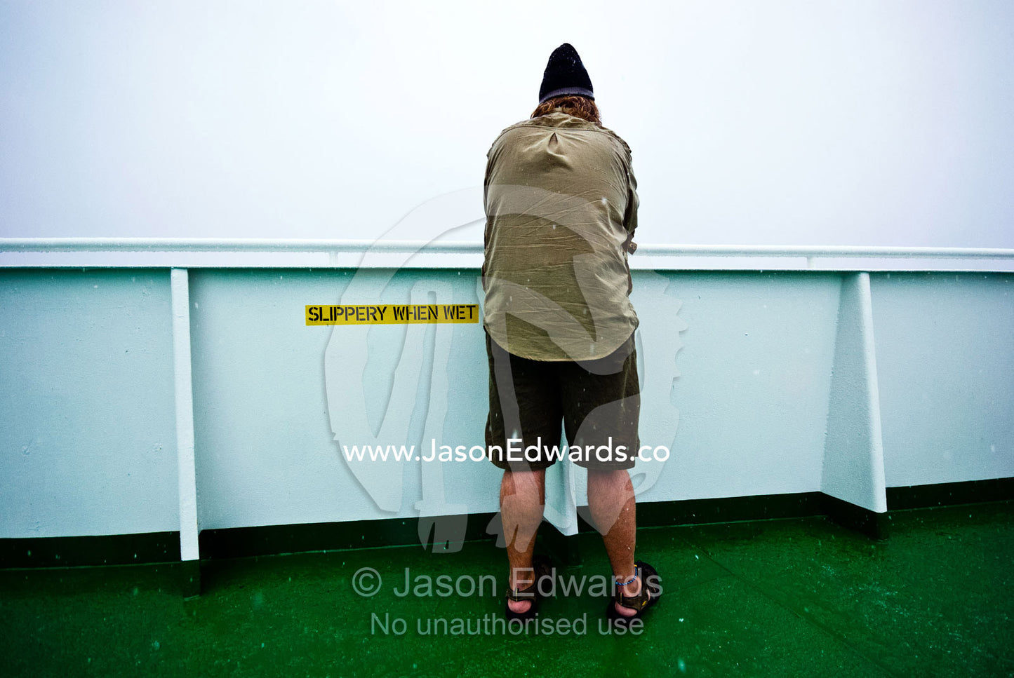 A tourist in shorts and sandals exposed to the bitter cold on a ship. Gerlache Strait, Graham Land, Antarctic Peninsula, Antarctica.