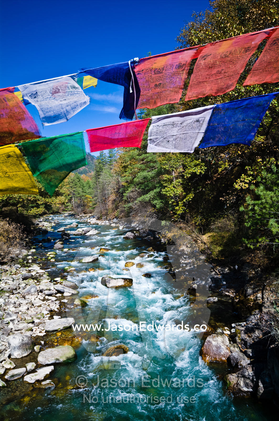 Colorful prayer flags fly over turquoise rapids in an alpine river. Thimphu Chu, Thimphu River, Thimphu, Thimphu District, Bhutan.