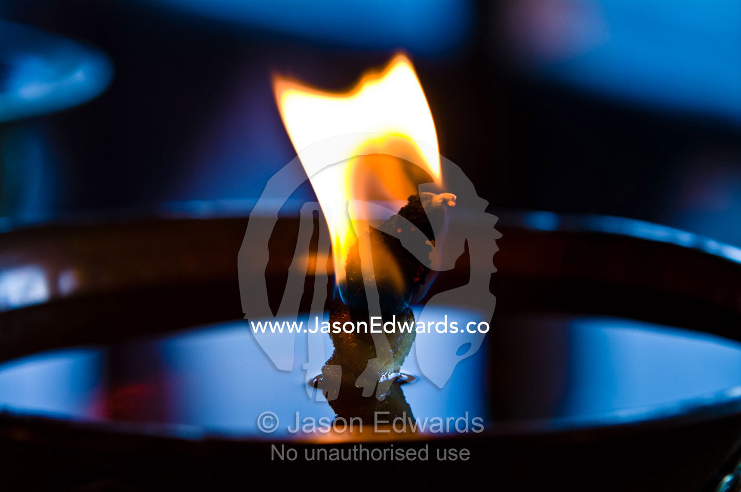 A flames burns serenely in a butter lamp in an ancient Buddhist monastery prayer room. Cheri Monastery, Chagri Dorjeden Monastery, Thimphu, Thimphu District, Bhutan.