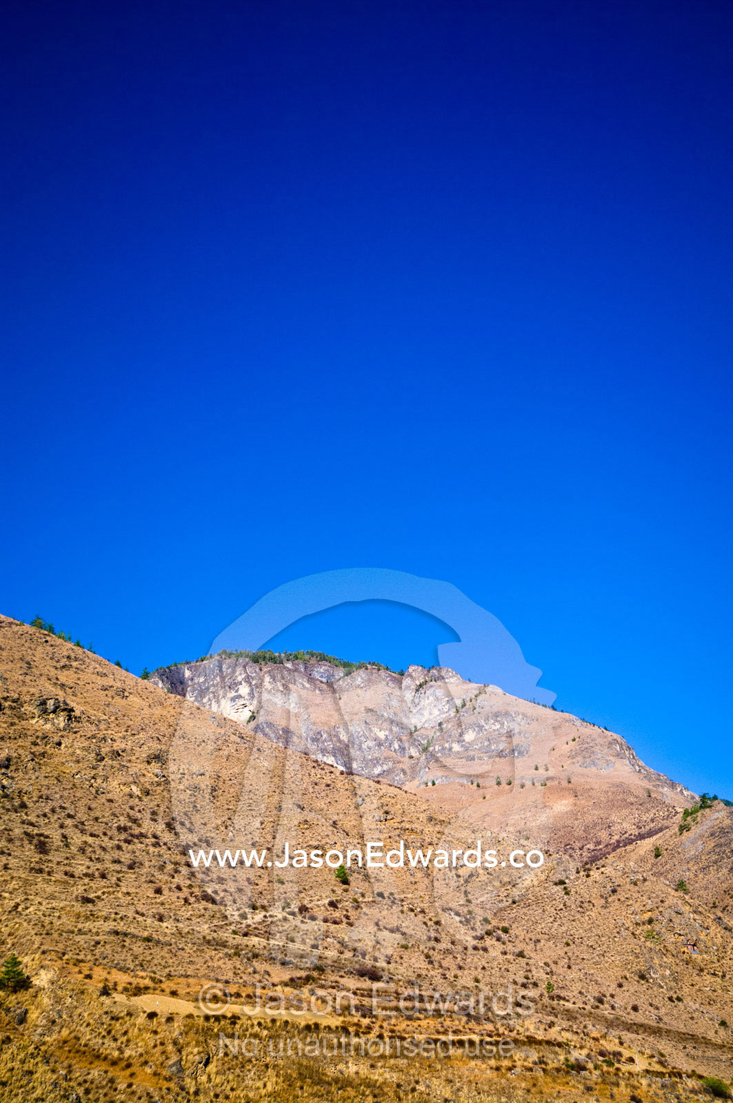 A bare and arid mountainside beneath a clear blue sky in the Himalayan Mountains. Thimphu District, Bhutan.