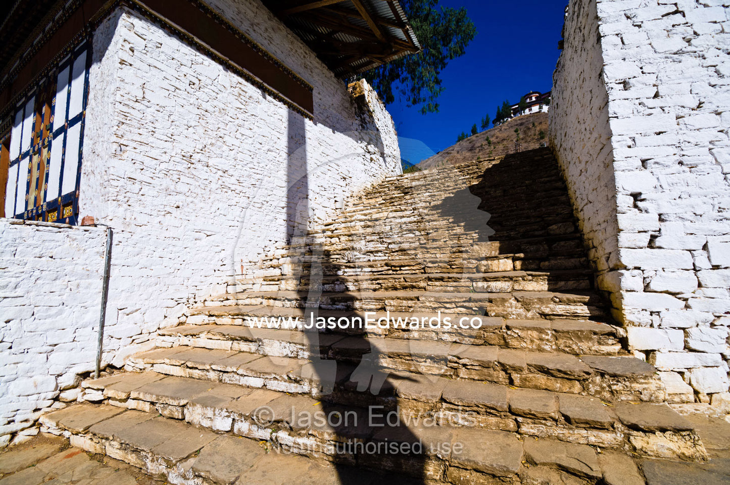 Ancient and weathered stone steps lead up a mountain through a monastery. Rinpung Dzong, Paro Dzong, Paro, Paro District, Bhutan.