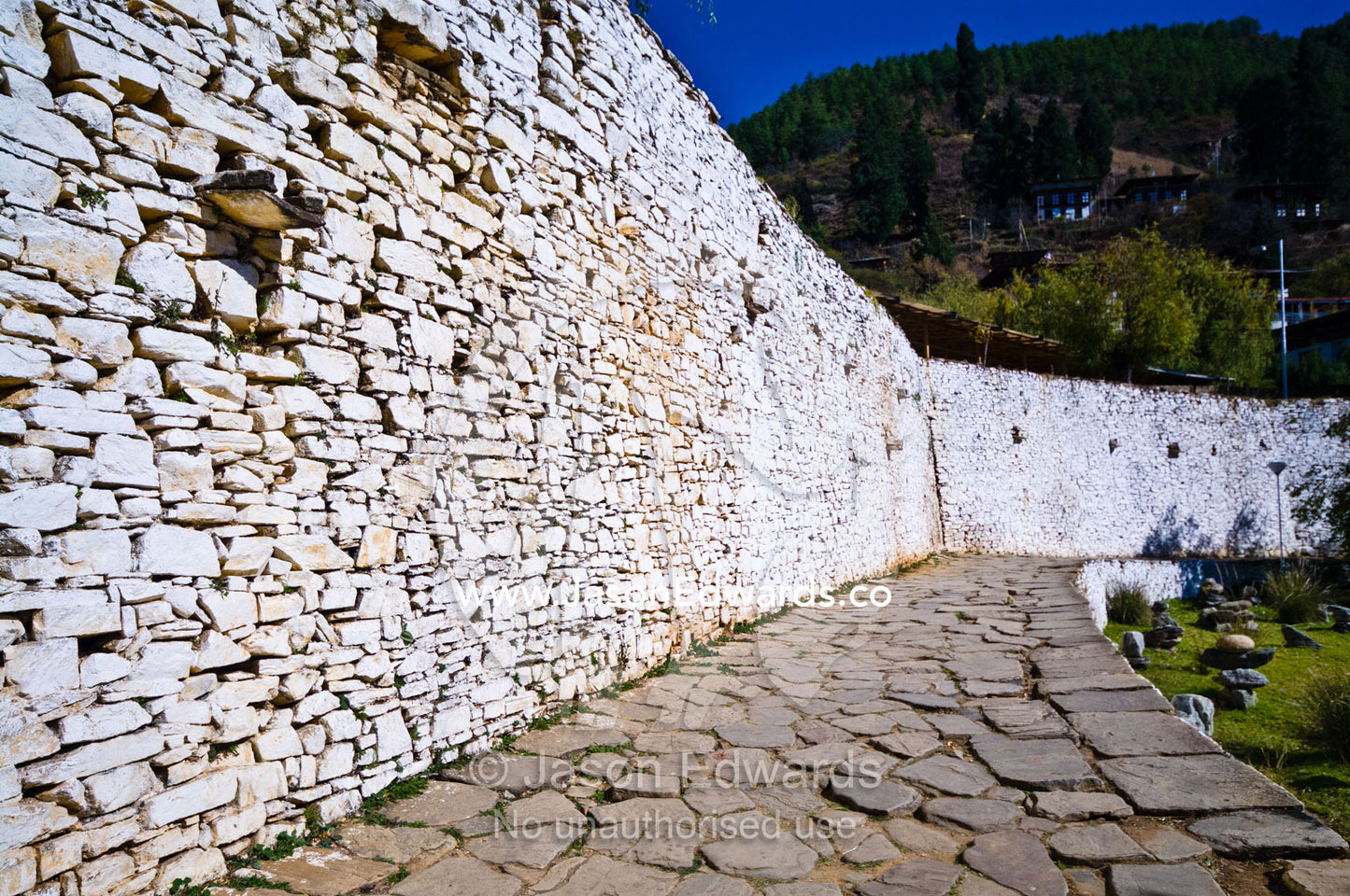 An ancient white-washed handmade stone wall and footpath in a Buddhist monastery. Rinpung Dzong, Paro Dzong, Paro, Paro District, Bhutan.