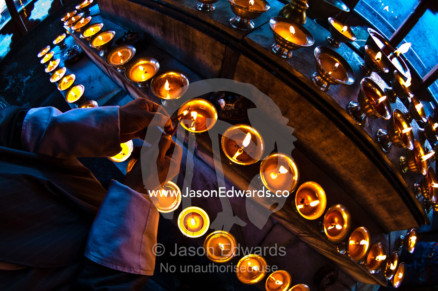 A Buddhist lights a butter lamp and offers prayers in a monastery in the Himalaya. Cheri Monastery, Chagri Dorjeden Monastery, Thimphu, Thimphu District, Bhutan.