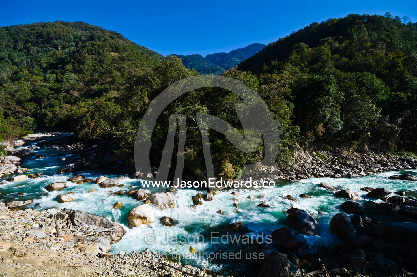 Turquoise rapids swirl around boulders in the current of a pristine Himalayan river. Punakha River, Punakha Valley, Punakha-Wangdiphodrang District, Bhutan.