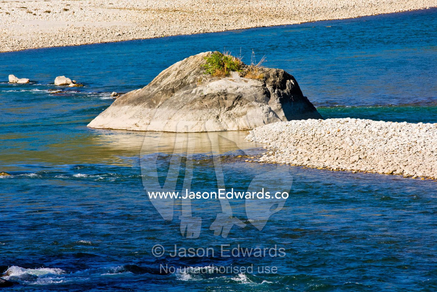 Eddies swirl around boulders in a wide and shallow river. Punakha District, Bhutan.