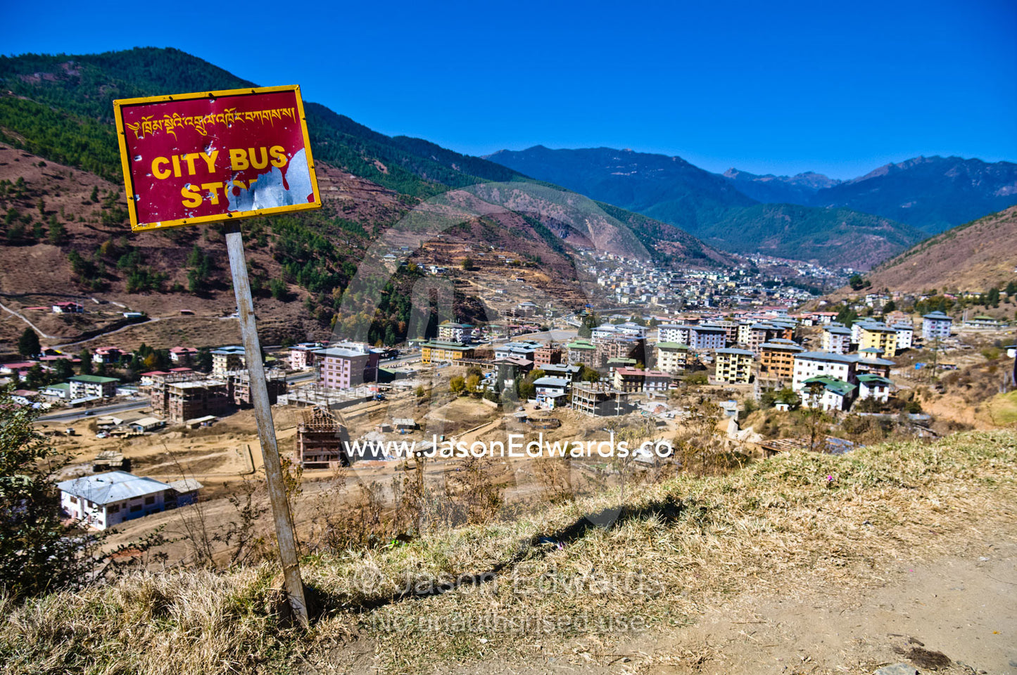 A weathered and beaten bus stop sign on a hilltop overlooking a Himalayan city. Thimphu, Thimphu District, Bhutan.