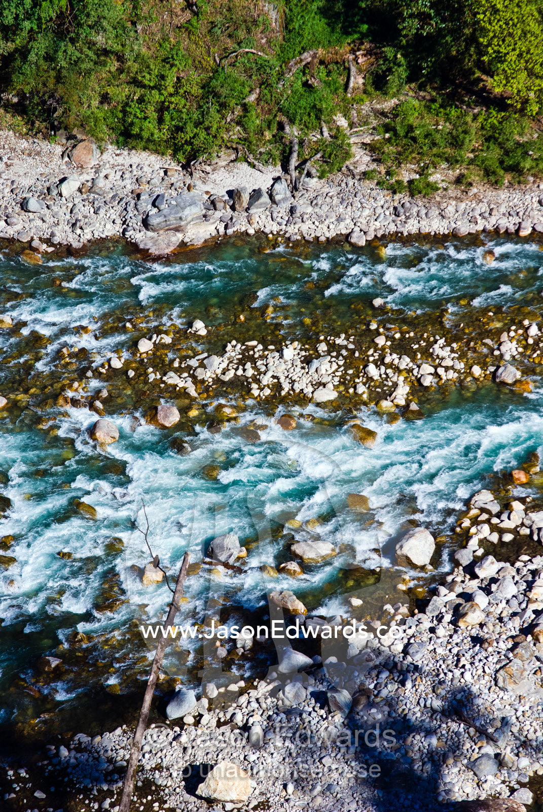 Turquoise rapids cascade over a boulder-strewn riverbed in a Himalaya valley. Jigme Dorji National Park, Gasa District, Bhutan.
