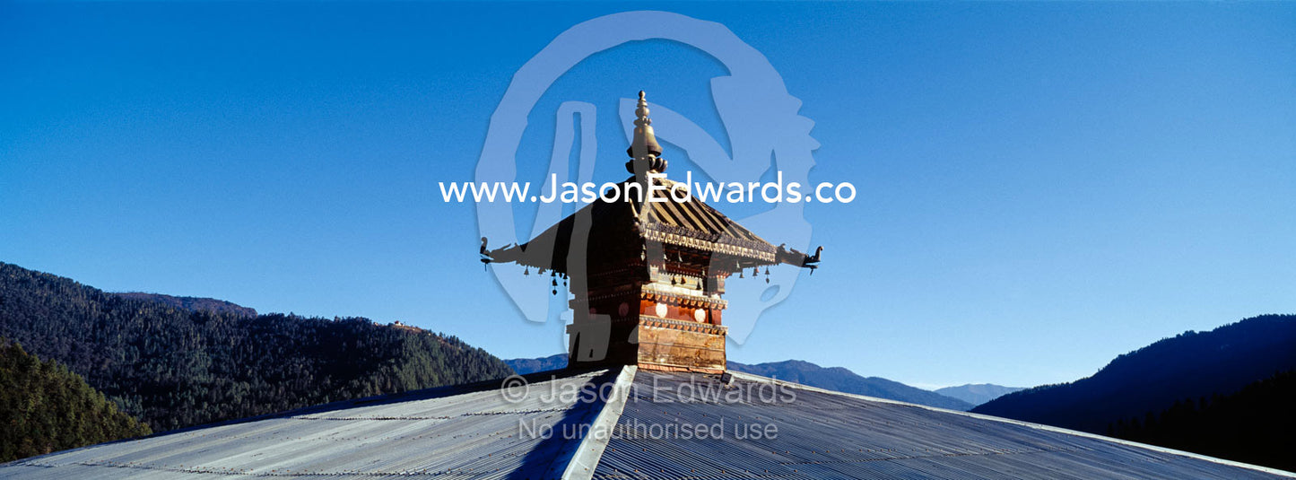 An ancient ornate roof spire rises above a corrugated tin roof recently replaced on a Buddhist monastery. Cheri Monastery, Chagri Dorjeden Monastery, Thimphu, Thimphu District, Bhutan.