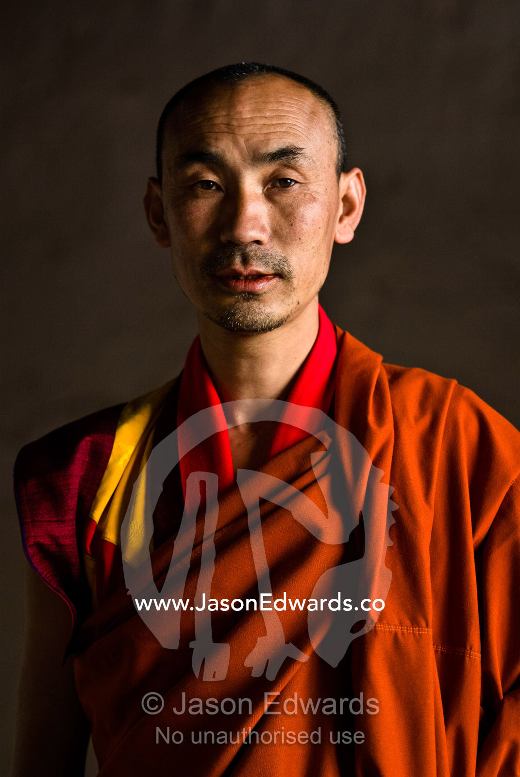 A senior Buddhist monk posing for a portrait in an ancient monastery. Punakha Dzong, Punakha dzongkhag, Punakha District, Bhutan.