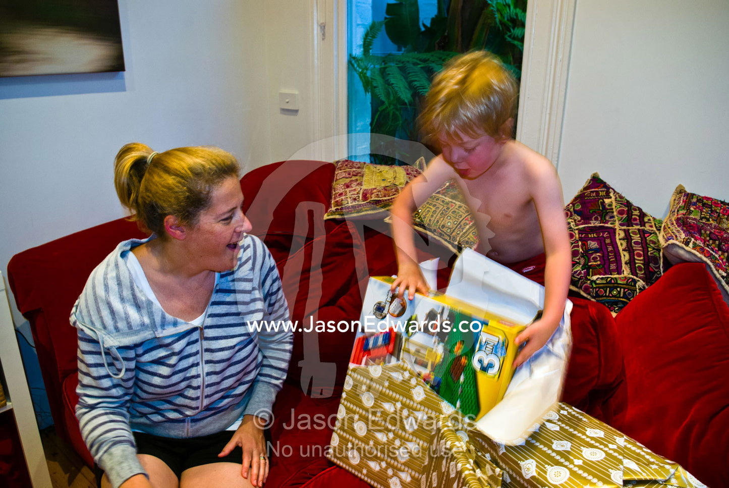 An excited boy unwraps a gift from Father Christmas on christmas day. Carlton North, Melbourne, Victoria, Australia.