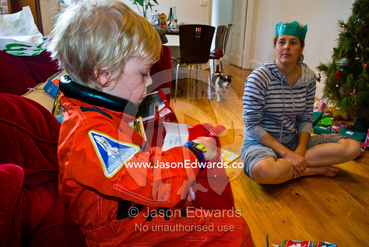 An excited boy unwraps a gift from Father Christmas on Christmas day. Carlton North, Melbourne, Victoria, Australia.
