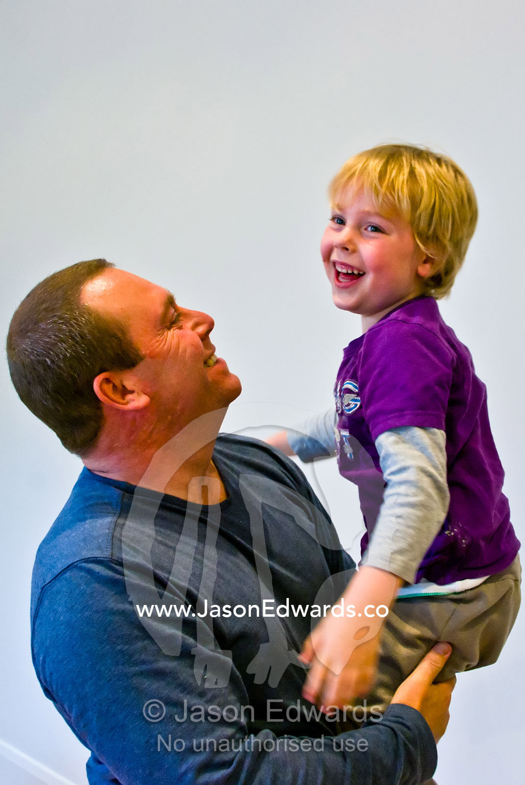 A father lovingly lifts his laughing son into the air whilst playing. Carlton North, Melbourne, Victoria, Australia.