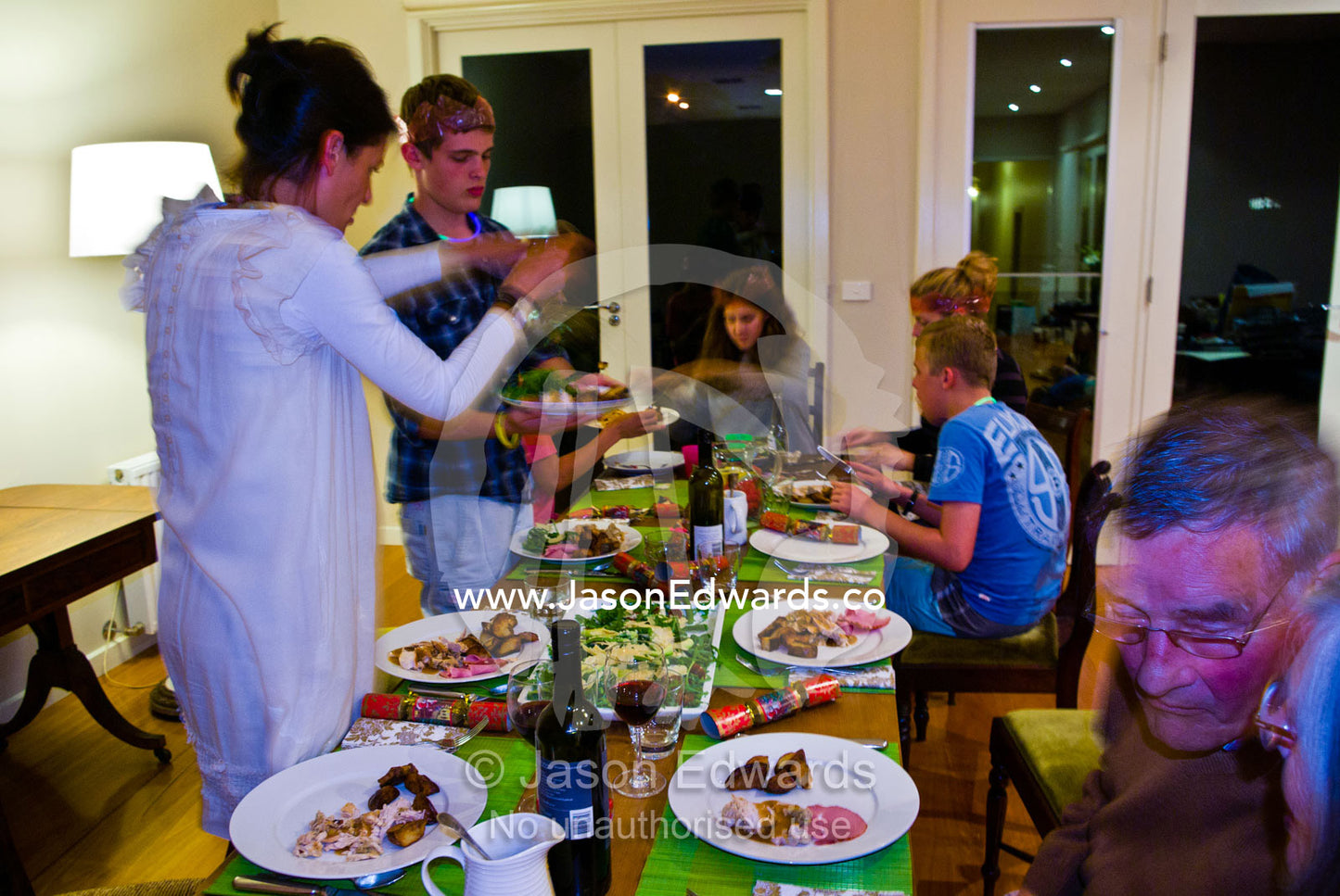 A family prepares for dinner at the dining table on christmas night. Malvern East, Melbourne, Victoria, Australia.
