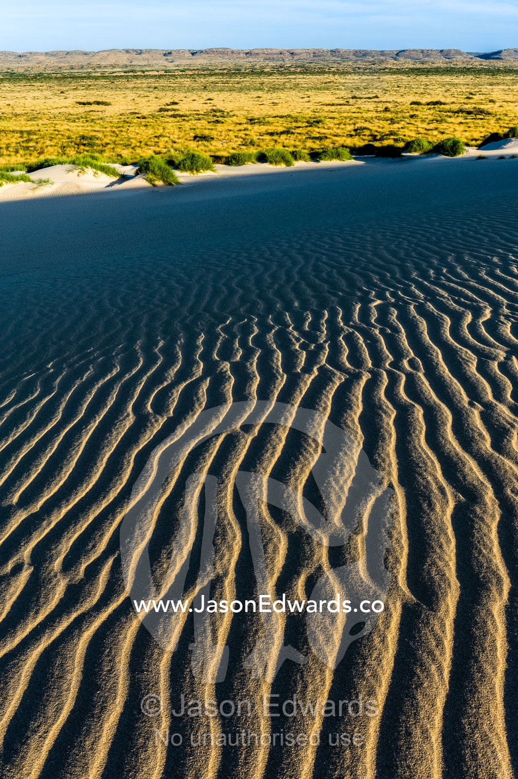 Shadows fall over ripples on a coastal desert sand dune at sunset. Cape Range National Park, Exmouth, Ningaloo Reef, Western Australia, Australia.