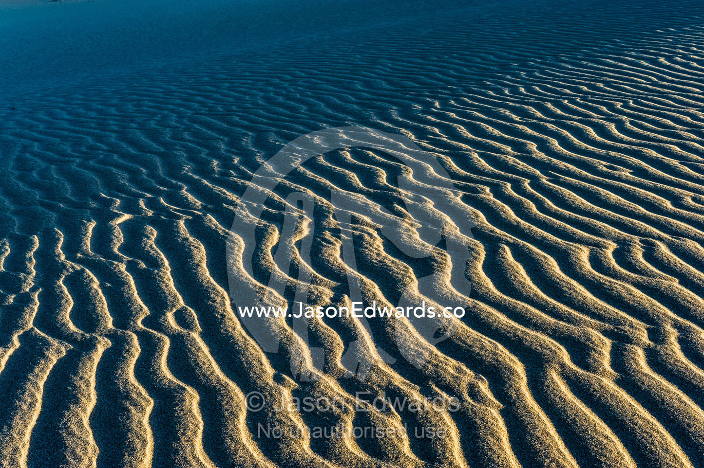 Shadows fall over ripples on a coastal desert sand dune at sunset. Cape Range National Park, Exmouth, Ningaloo Reef, Western Australia, Australia.