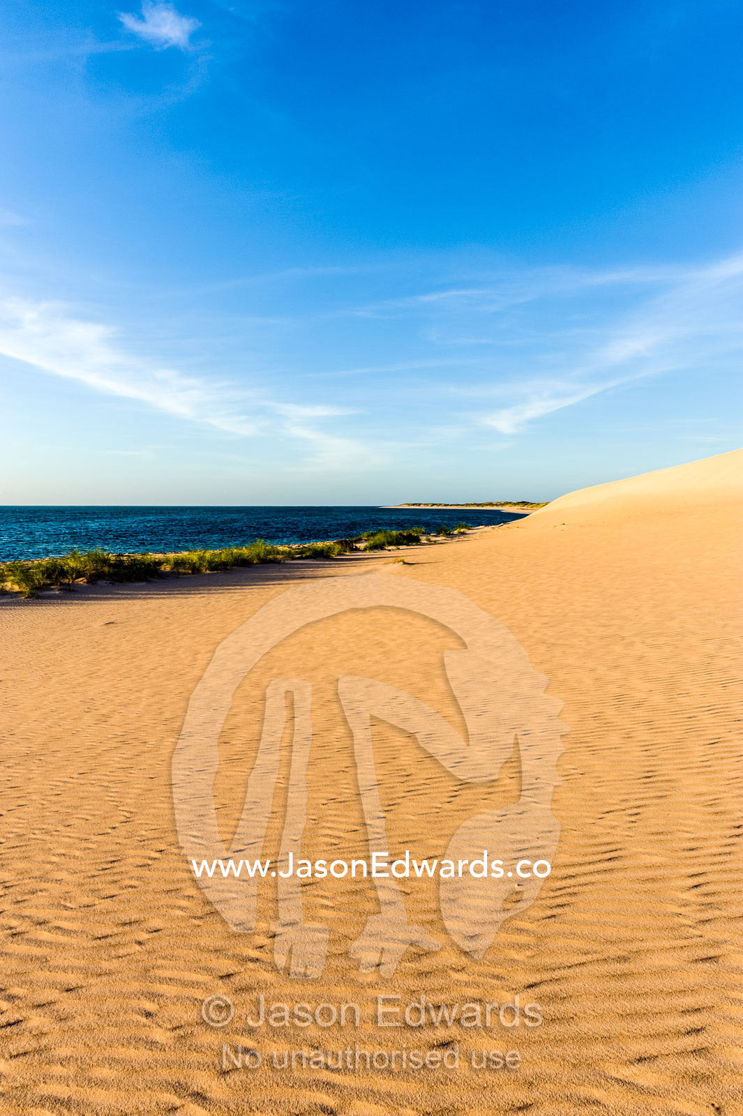 Sweeping coastal desert sand dunes flow into tropical seas at sunset. Cape Range National Park, Exmouth, Ningaloo Reef, Western Australia, Australia.