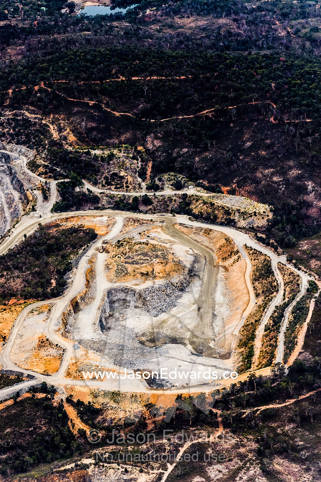 Aerial view of an open-cut mine and denuded forest on nearby hills. Perth, Western Australia, Australia.