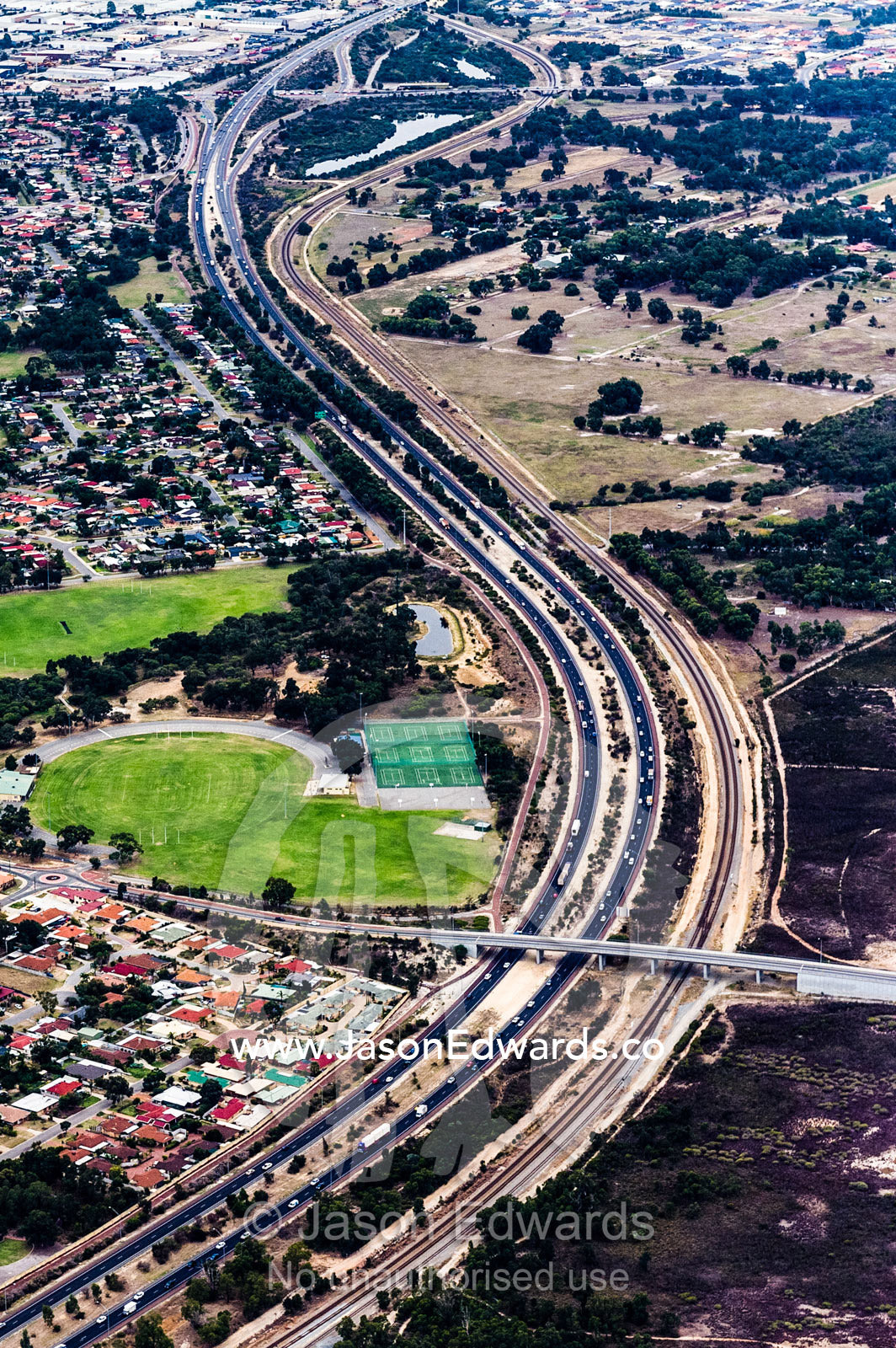 A highway snakes it's way around houses jammed in a suburban sprawl. Perth, Western Australia, Australia.