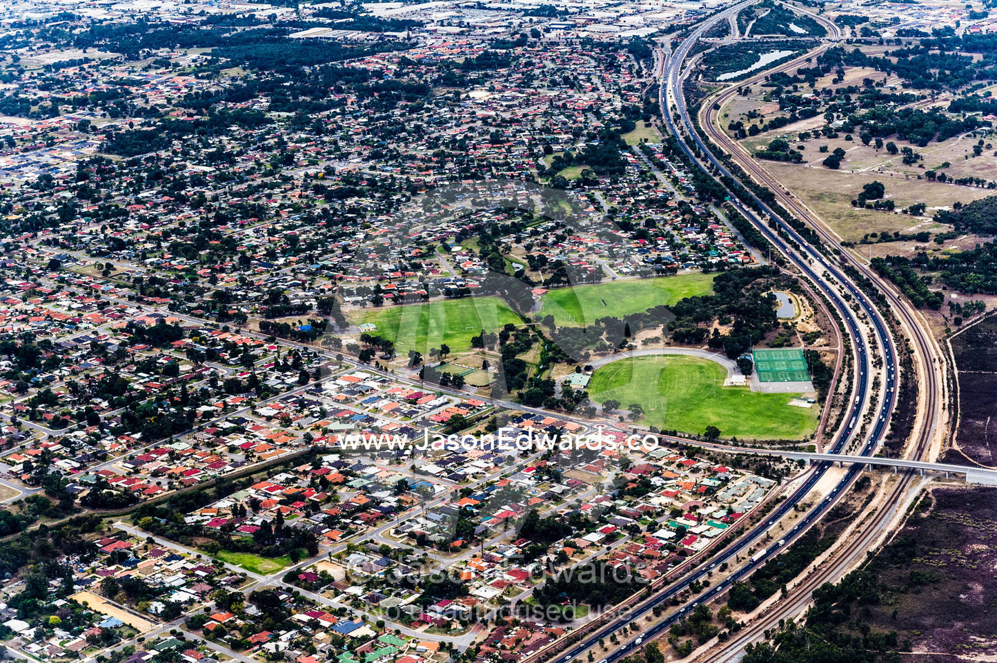 A highway snakes it's way around houses jammed in a suburban sprawl. Perth, Western Australia, Australia.