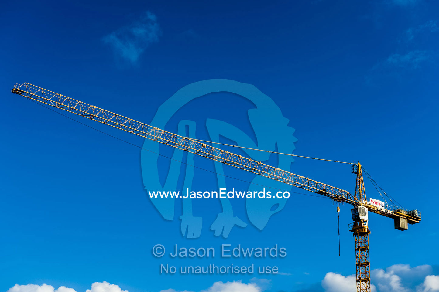 A construction crane boom stretches out into a clear blue sky. Cape Town, Victoria and Alfred Waterfront, Western Cape, South Africa.