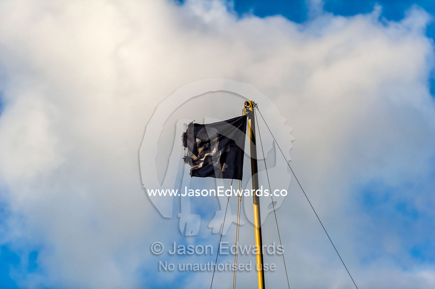 A Jolly Roger pirate flag flying from the mast of a yacht. Cape Town, Victoria and Alfred Waterfront, Western Cape, South Africa.