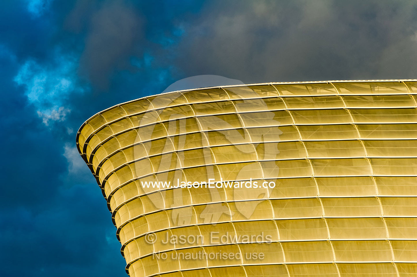 A storm turns the architecture of Cape Town Stadium golden at sunset. Cape Town Stadium, Cape Town, Western Cape, South Africa.