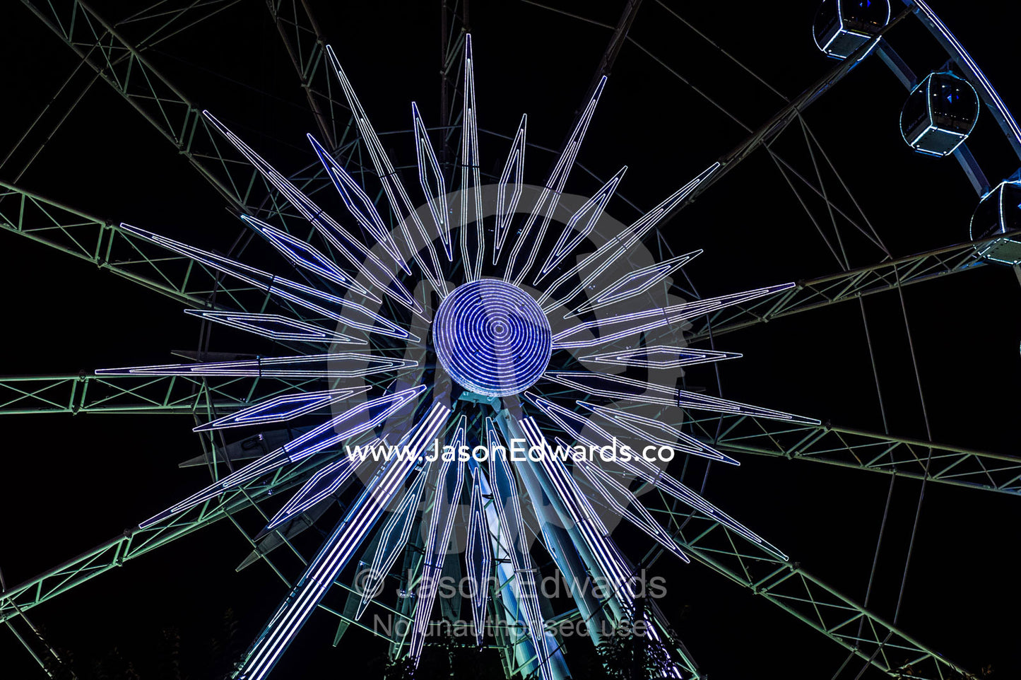 A ferris wheel illuminated by neon lights in a marina shopping district. Cape Town, Victoria and Alfred Waterfront, Western Cape, South Africa.
