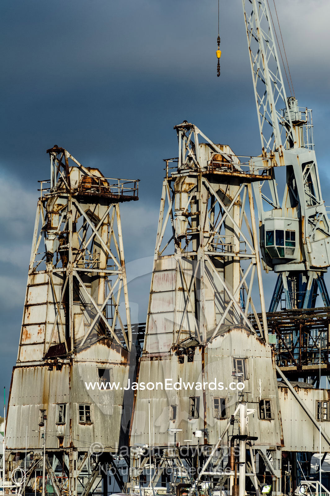 Rusting industrial crane towers and warehouses on a marina wharf. Cape Town, Victoria and Alfred Waterfront, Western Cape, South Africa.