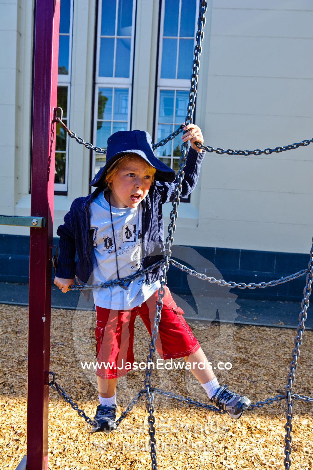 A boy explores the playground equipment on his first day of school. Carlton North, Melbourne, Victoria, Australia.