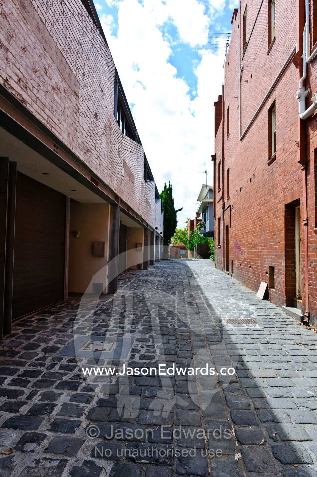 A blue-stone cobbled lane behind inner city warehouses and townhouses. North Melbourne, Melbourne, Victoria, Australia.