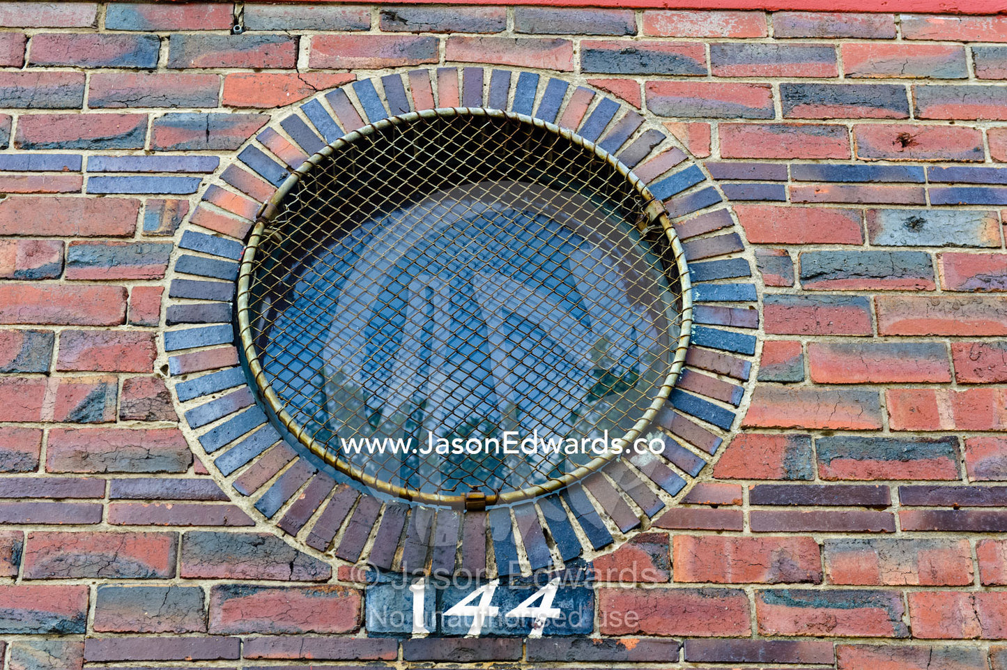 A circular brick window with a wire security screen over the glass. North Melbourne, Melbourne, Victoria, Australia.