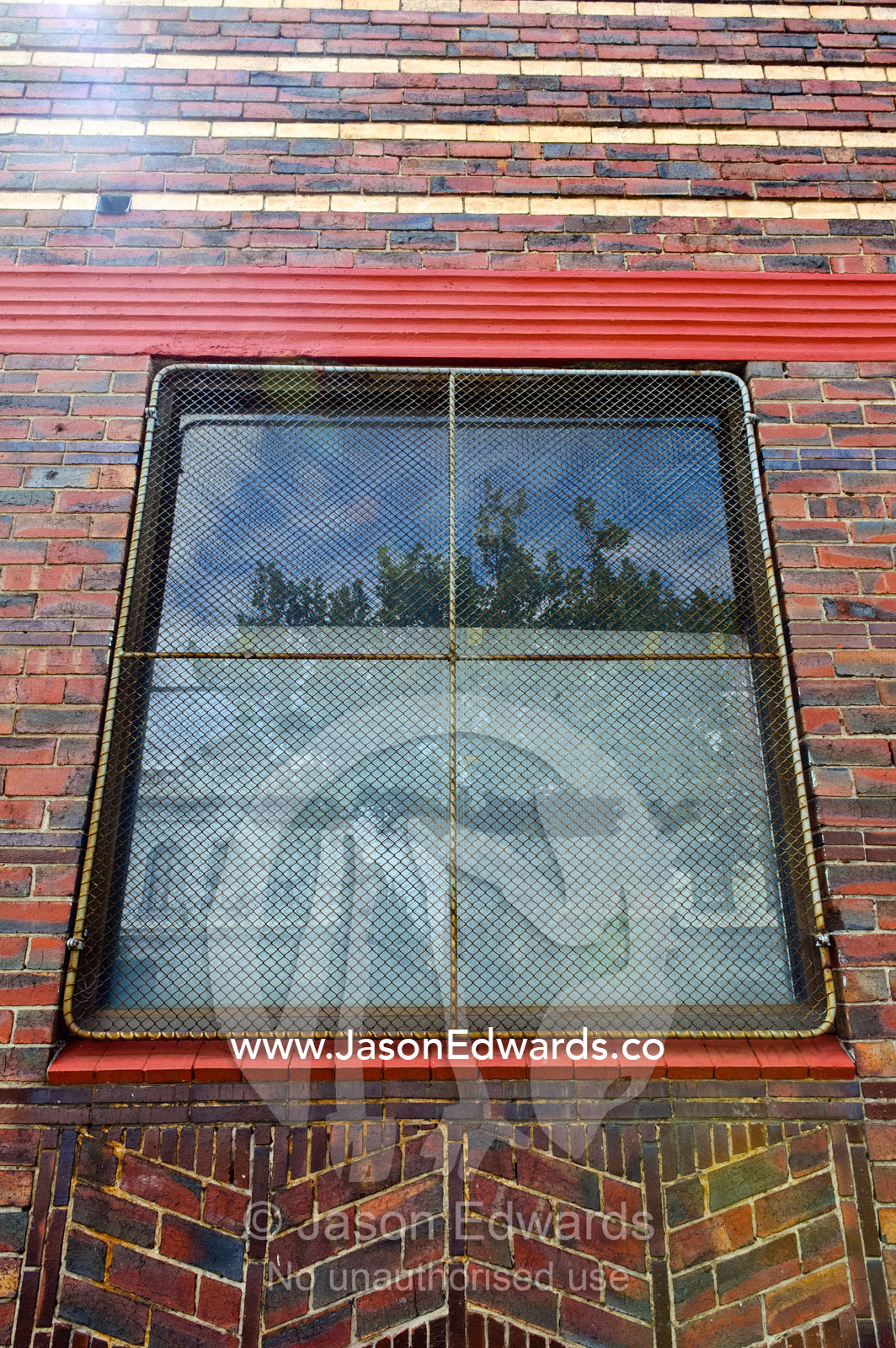 A square window in a red brick wall with a wire security screen. North Melbourne, Melbourne, Victoria, Australia.