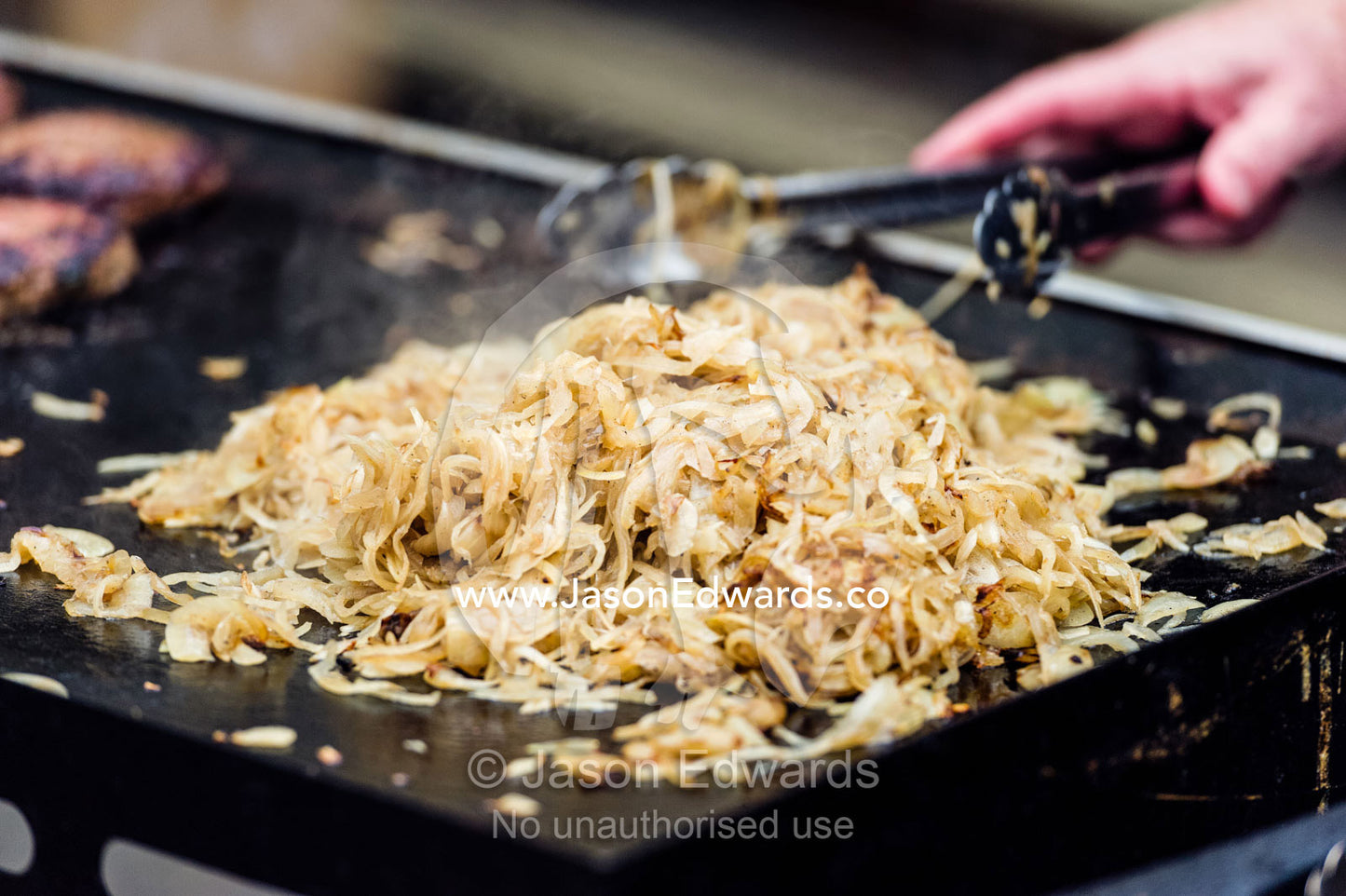 Fresh onion is grilled on a barbecue hot plate at a school fete. Carlton North, Melbourne, Victoria, Australia.