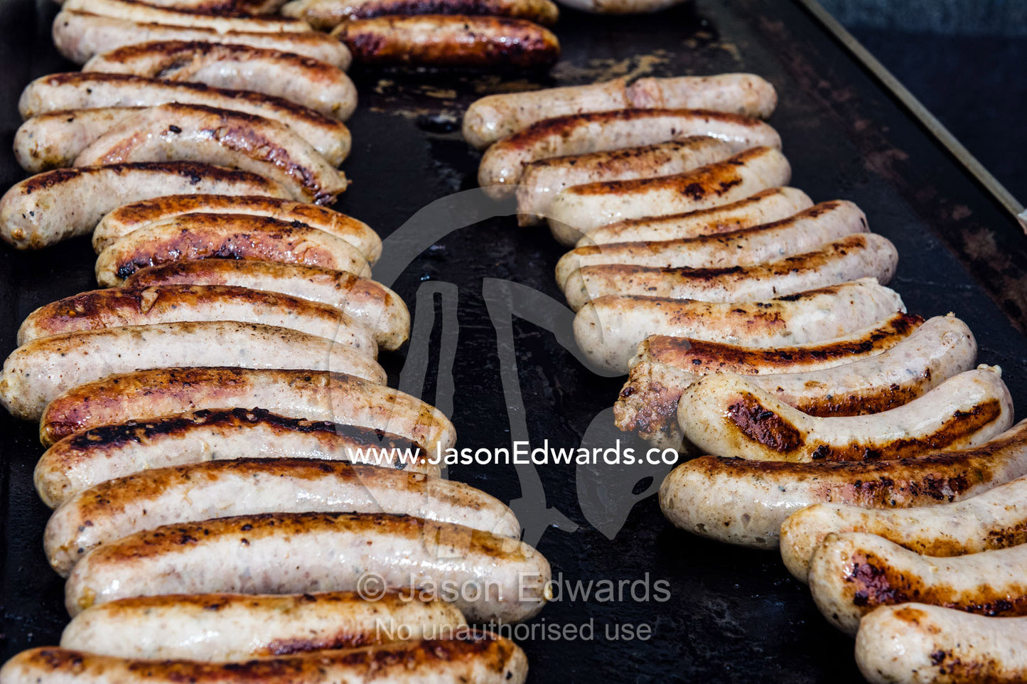 Rows of sausages grilling on a barbecue at a school fete fundraiser. Lee Street Primary School, Carlton North, Melbourne, Victoria, Australia.
