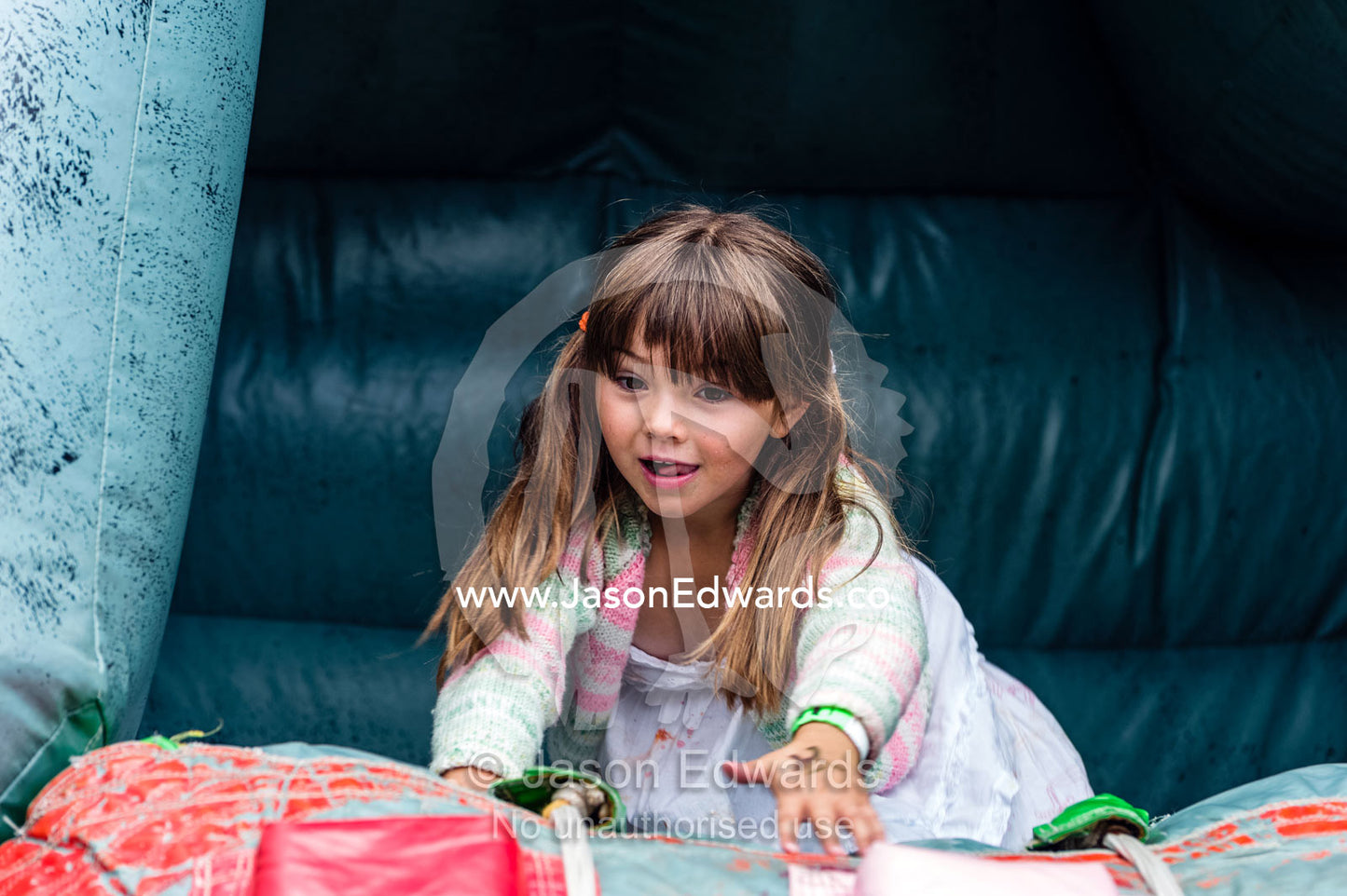 A girl laughing as he plays on an inflatable castle at a school fete. Carlton North, Melbourne, Victoria, Australia.
